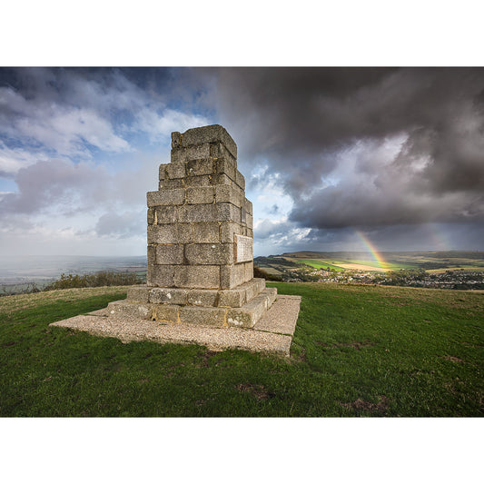 Image number 3081 by Available Light Photography showcases The Worsley Monument atop a grassy hill under cloudy skies, with a distant rainbow spanning the landscape.