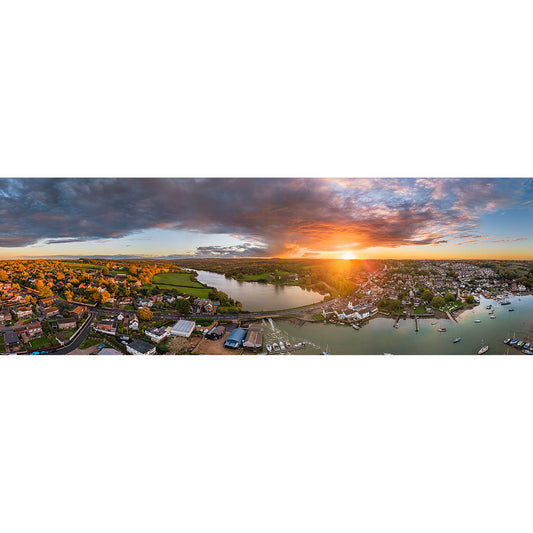 Aerial view of Wootton Bridge at sunset by Available Light Photography, showcasing riverside houses, boats, and a bridge beneath a partly cloudy sky.