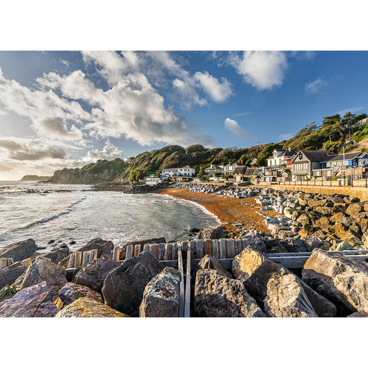 Steephill Cove by Available Light Photography features a rocky shoreline, sandy beach, coastal houses, and lush green cliffs beneath a partly cloudy sky with gentle waves and sunlight brightening the tranquil scene.