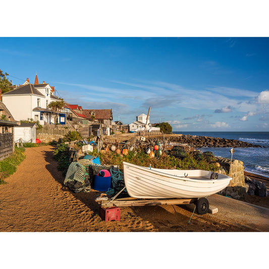 Steephill Cove by Available Light Photography features a small white boat on a sandy path near fishing nets and gear, with coastal houses and the sea in the background under a clear blue sky.