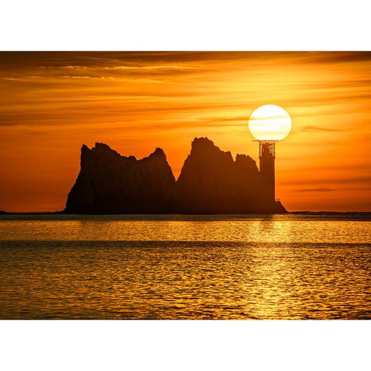 The Needles by Available Light Photography features a lighthouse silhouetted against an orange sunset, the sun appearing to rest atop the beacon near rugged sea stacks.