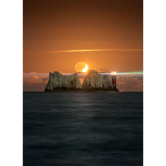 Moonset at The Needles by Available Light Photography captures a crescent moon setting behind rocky sea stacks and a lighthouse, casting an orange glow over the ocean at dusk.