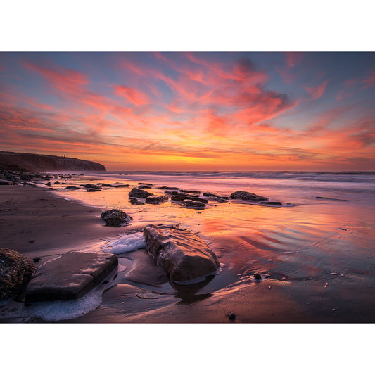 Culver Cliff by Available Light Photography captures a rocky beach at sunset with vibrant pink and orange clouds mirrored on wet sand, as gentle ocean waves shimmer softly in the tranquil background.