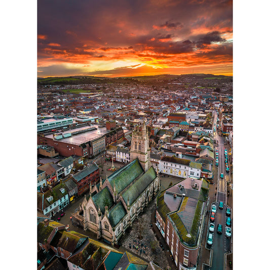 Aerial view of Newport at sunset, captured by Available Light Photography, highlights a central stone church surrounded by buildings and roads with cars.