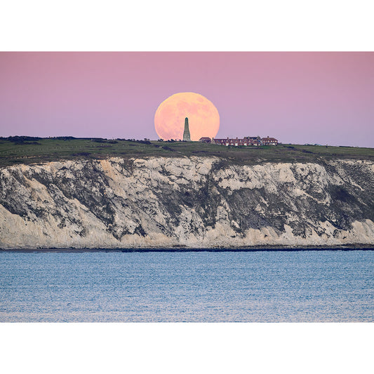 Wolf Moon over Culver Cliff" by Available Light Photography captures a large full moon rising behind a monument and buildings atop Culver Cliff, overlooking the sea under a dreamy pink and purple dusk sky.