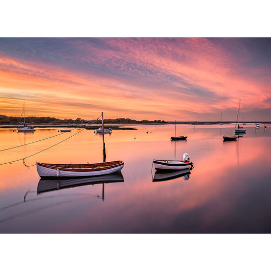 Newtown Creek by Available Light Photography captures small boats floating on calm water at sunset, with a vibrant sky reflected on the surface and additional anchored vessels in the distance.