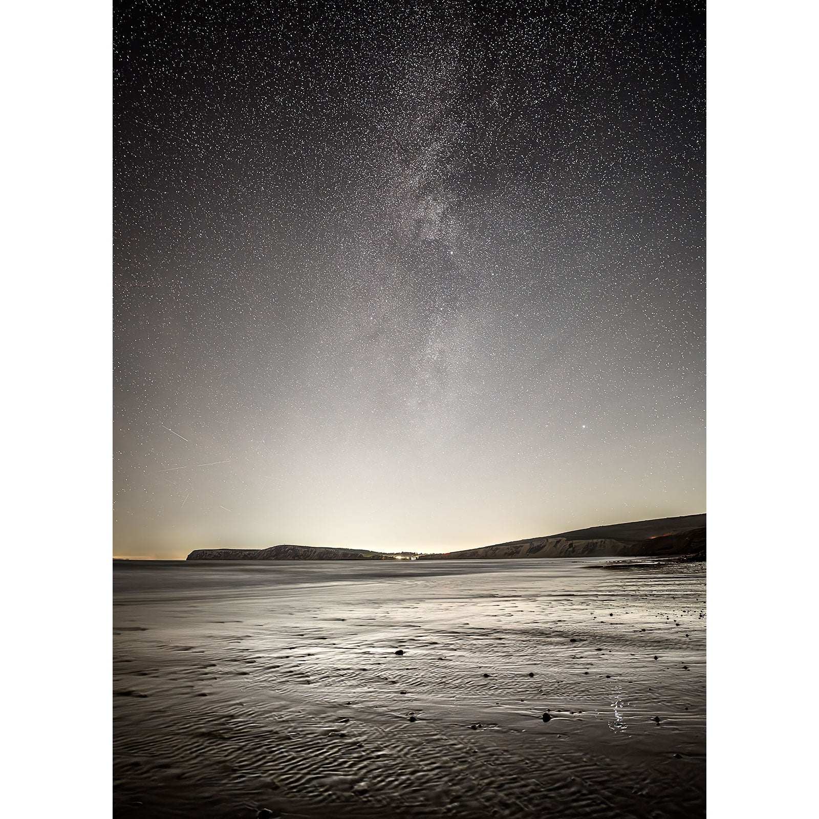 The Milky Way, Compton Bay by Available Light Photography captures a serene night beach scene under a starry sky, with distant cliffs on the horizon and the faint shimmer of the Milky Way above.