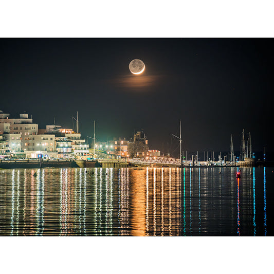 Crescent Moon over Cowes by Available Light Photography captures a low-hanging moon above the harbor, with sailboats gliding past modern buildings and shimmering reflections on calm nighttime waters.