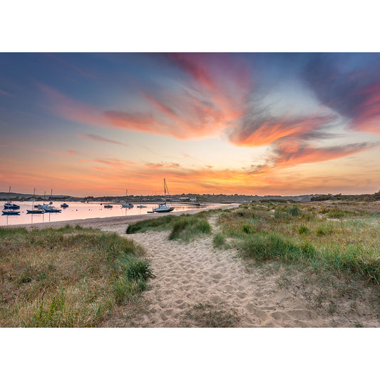 Sunset over a tranquil Bembridge Harbour with colorful sky and boats anchored near a grassy shore, captured by Available Light Photography.