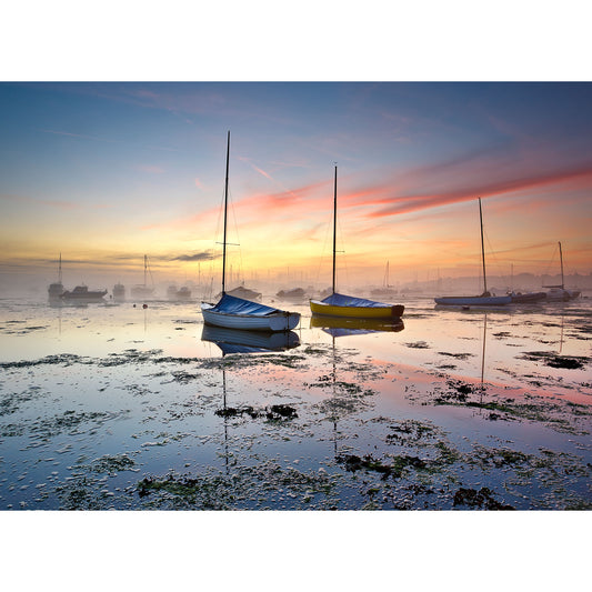 Boats on a calm water surface at sunrise with mist and a colorful sky, captured by Steve at Bembridge Harbour by Available Light Photography.