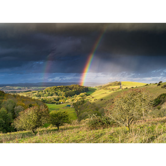 A vibrant double rainbow over a lush, hilly landscape with Storm over the Downs above on the Isle of Wight by Available Light Photography.