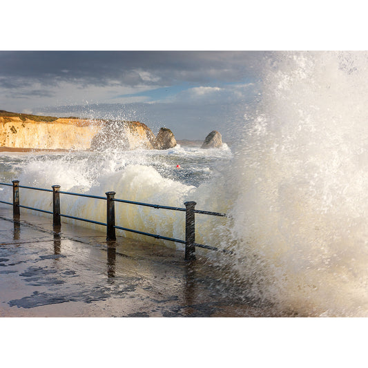 Freshwater Bay waves crash over a seaside railing on the Isle of Wight under a cloudy sky. (Available Light Photography)