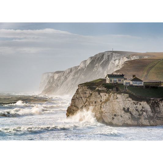 Freshwater Bay chalk cliffs against a turbulent sea with a small building perched at the edge of the Isle of Wight, captured by Available Light Photography.