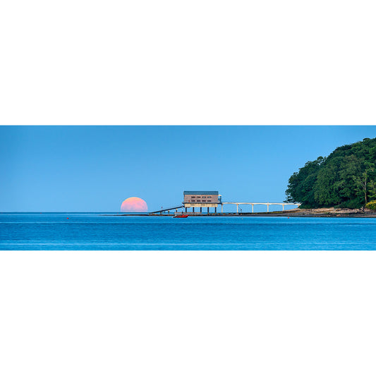 Sunset behind a building on a pier extending into the sea, with a wooded coastline to the right on the Isle of Wight, captured by Available Light Photography's Strawberry Moonrise at Bembridge Lifeboat Station.