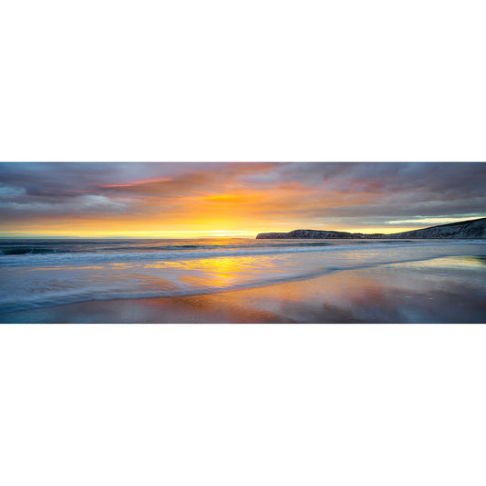 Sunset over Compton Bay on the Isle of Wight with waves gently washing onto shore and vibrant colors reflecting on the water's surface, captured by Available Light Photography.
