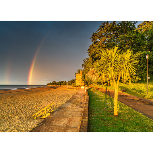 A coastal promenade on the Isle with a rainbow over the sea during golden hour captured by Appley Tower from Available Light Photography.