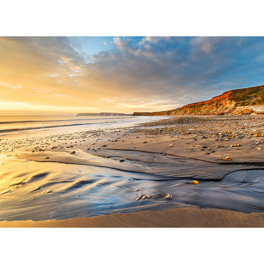 Sunset over Brook Bay beach on the Isle of Wight, with patterns in the sand and cliffs in the distance. (Brand Name: Available Light Photography)