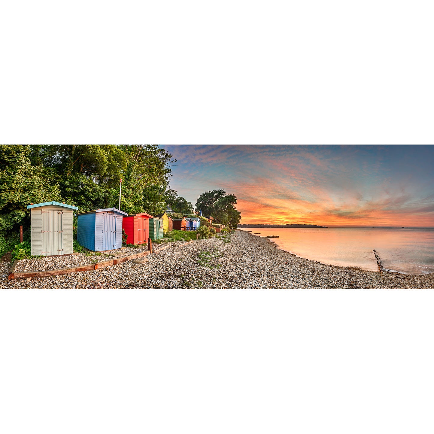 Colorful Bembridge Beach huts line a pebbly shore at sunset on the Isle of Wight captured by Available Light Photography.