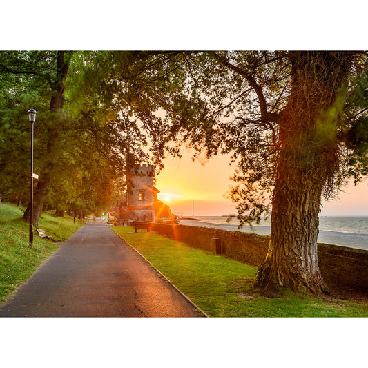 Pathway beside a beach at sunset with trees and an old Appley Tower building from Available Light Photography.