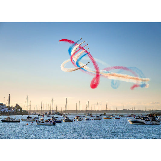 Jets performing an aerial display with red, white, and blue smoke trails over the Isle of Wight harbor with boats featuring The Red Arrows at Cowes Week captured by Available Light Photography.