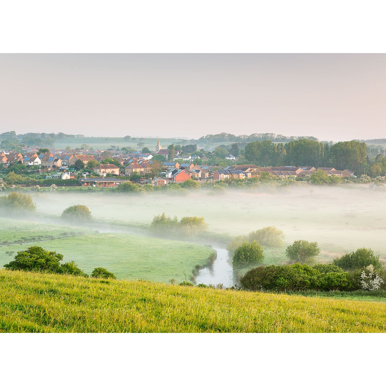A tranquil morning scene of an isle village enveloped in mist with surrounding greenery captured by Brading by Available Light Photography.