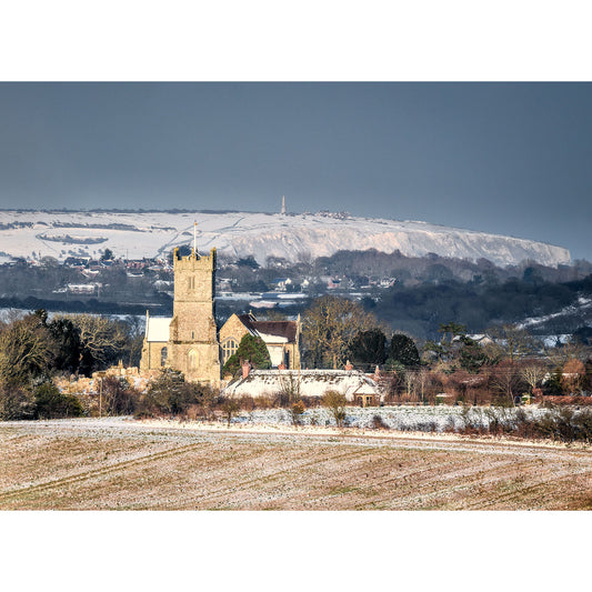 A Godshill Church on the Isle of Wight and surrounding landscape dusted with snow, with Culver Cliff blanketed in snow in the background. Photography by Available Light Photography.