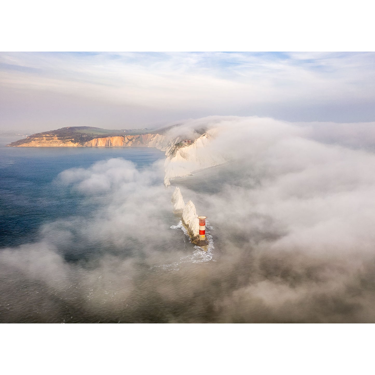Fog over The Needles engulfed by sea fog with towering cliffs on the Isle of Wight in the background. Shot by Available Light Photography.