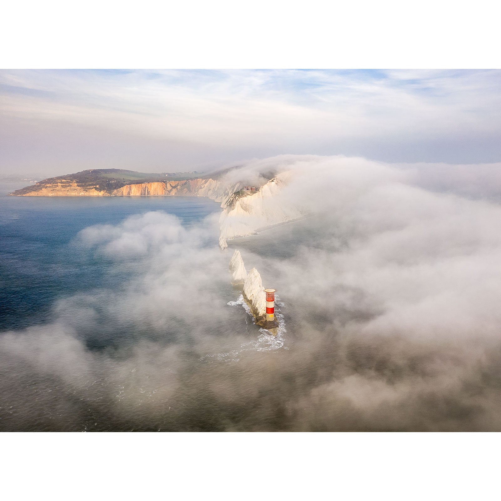 Fog over The Needles engulfed by sea fog with towering cliffs on the Isle of Wight in the background. Shot by Available Light Photography.