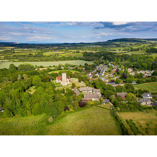Aerial view of Godshill, a quaint village on the Isle of Wight surrounded by green fields and trees under a clear sky taken by Available Light Photography.