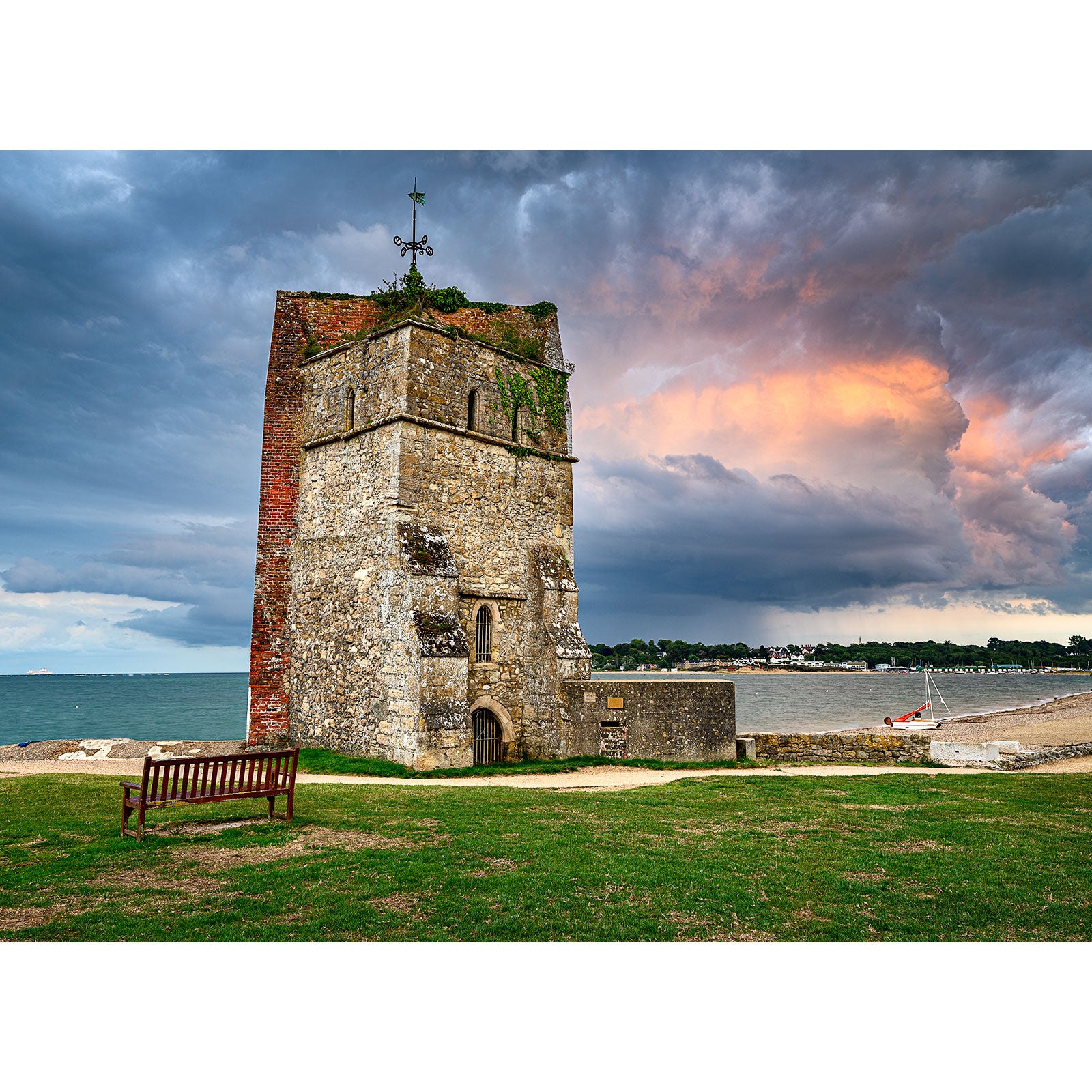 An ancient stone tower with vegetation growth under a dramatic sky at the edge of a coastline on the Isle of Wight captured by Available Light Photography's St. Helens Old Church.