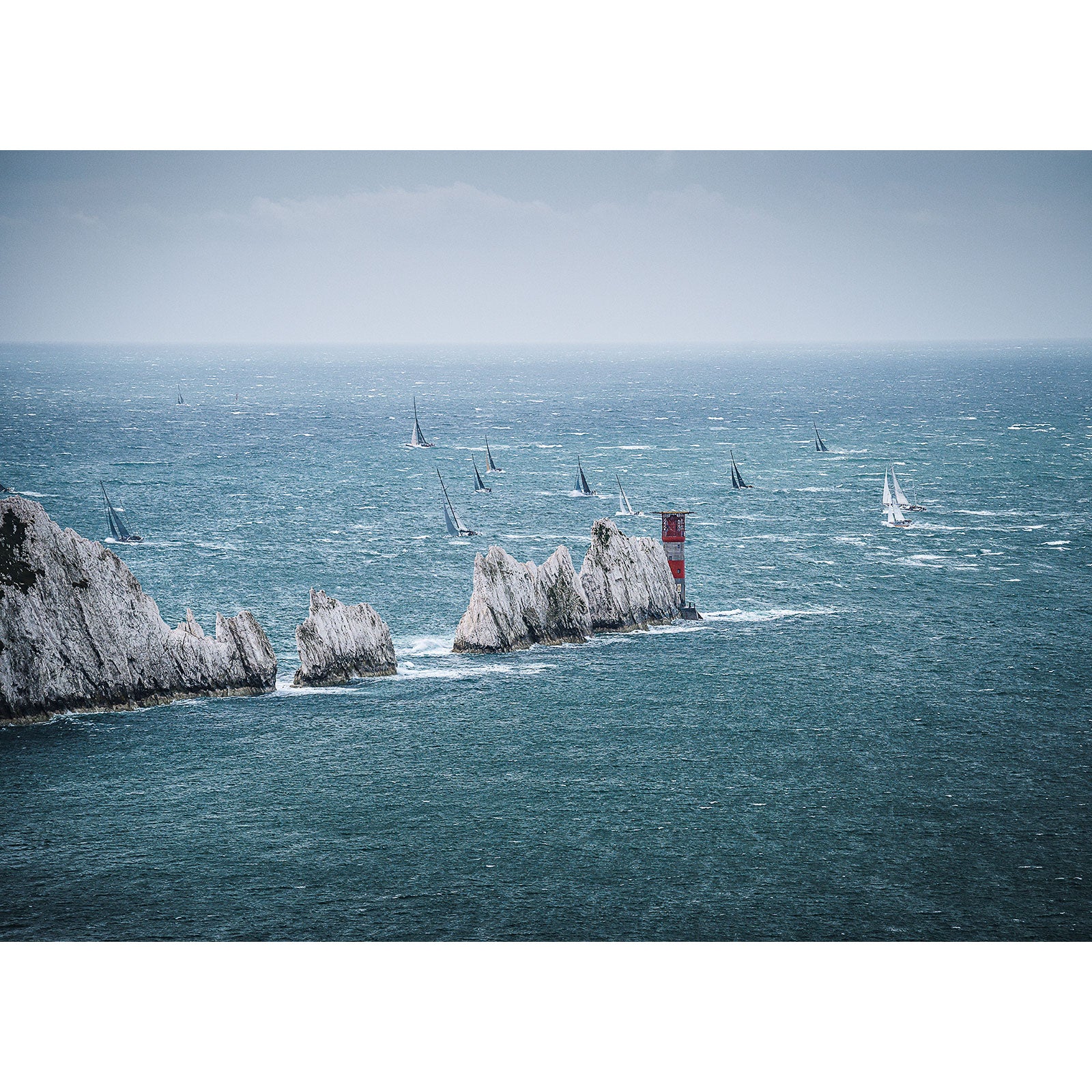 Sailing boats navigating past the chalk cliffs of the Isle of Wight on a breezy day during the Fastnet Race at The Needles captured by Available Light Photography.
