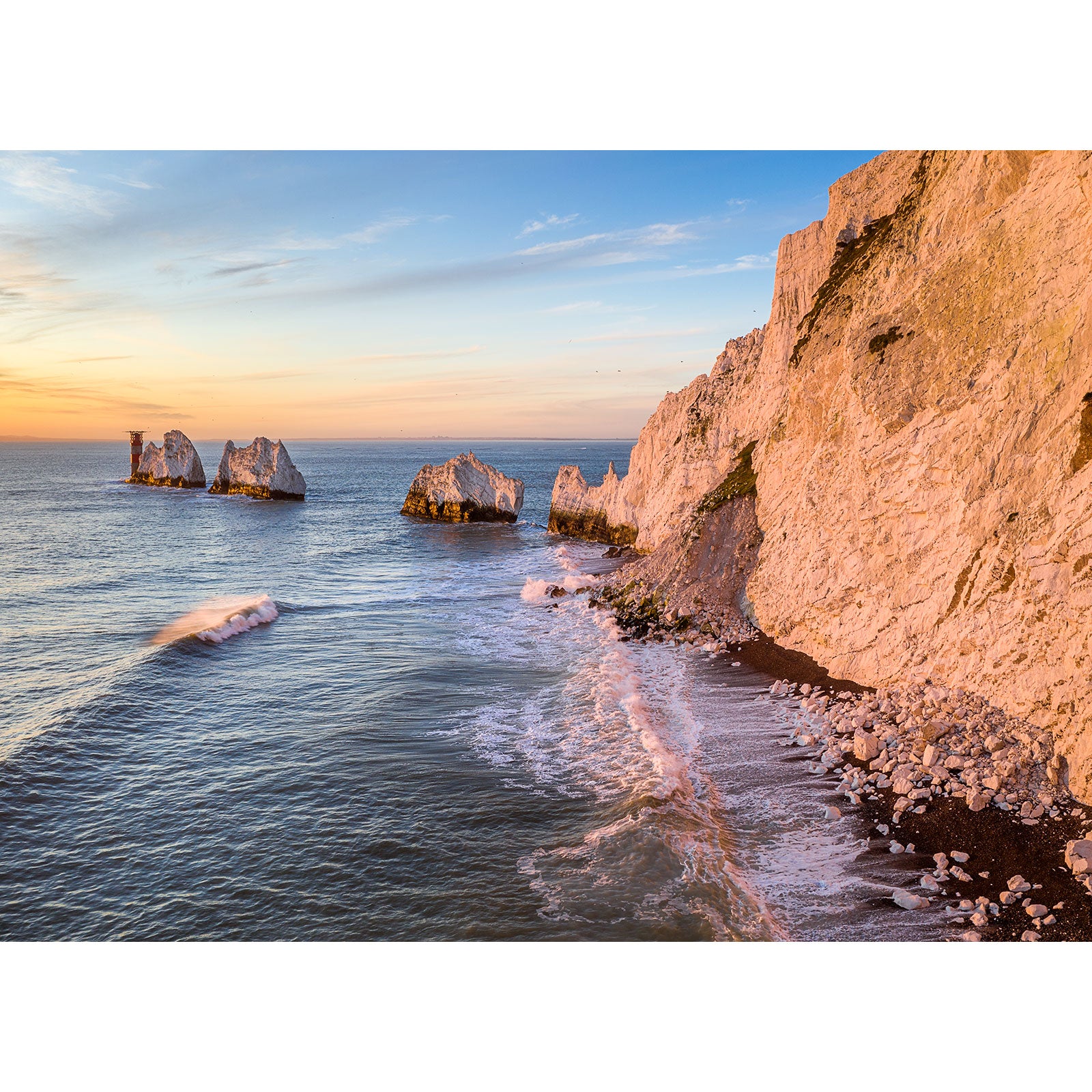 Golden sunlight illuminating a coastal scene with cliff faces and rock formations at sea on the Isle of Wight, captured beautifully by "The Needles" from Available Light Photography.