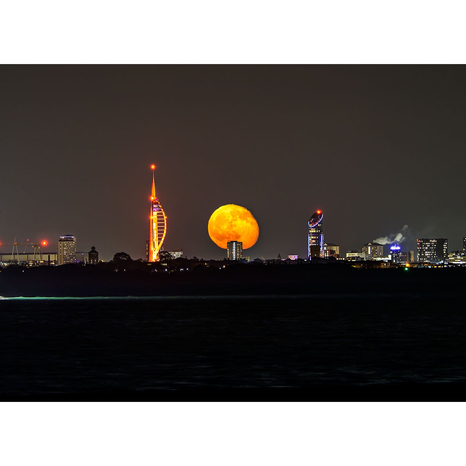 A Moonrise over The Spinnaker Tower rises behind the Gascoigne city skyline at night.