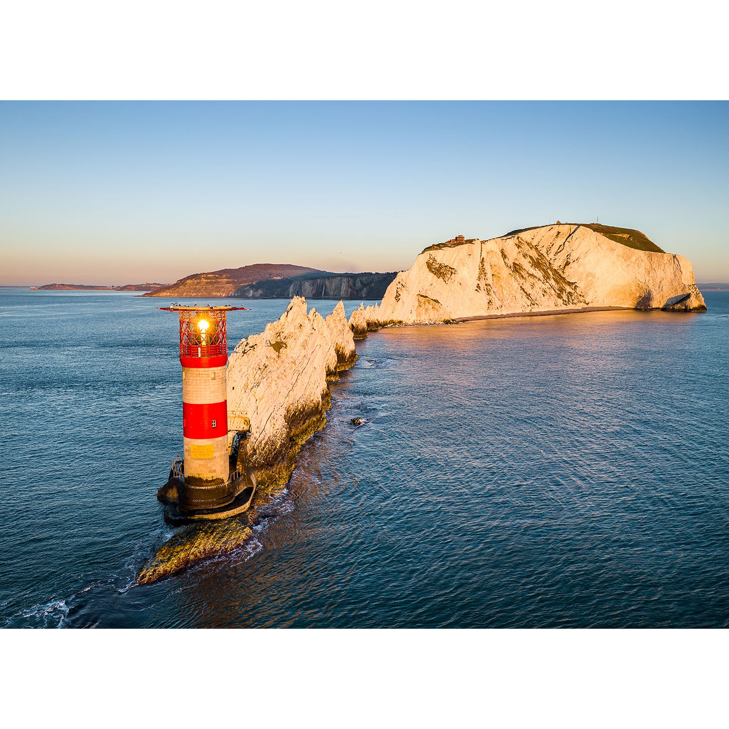 Aerial view of The Needles lighthouse on the Isle of Wight coastal cliff at sunset, captured by Available Light Photography.