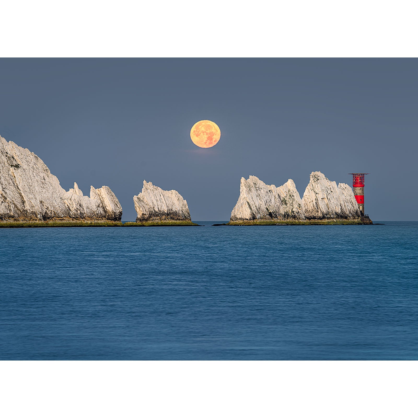 Full Moonset over The Needles rising over a calm sea with a lighthouse and white cliffs on the Wight horizon, captured by Available Light Photography.