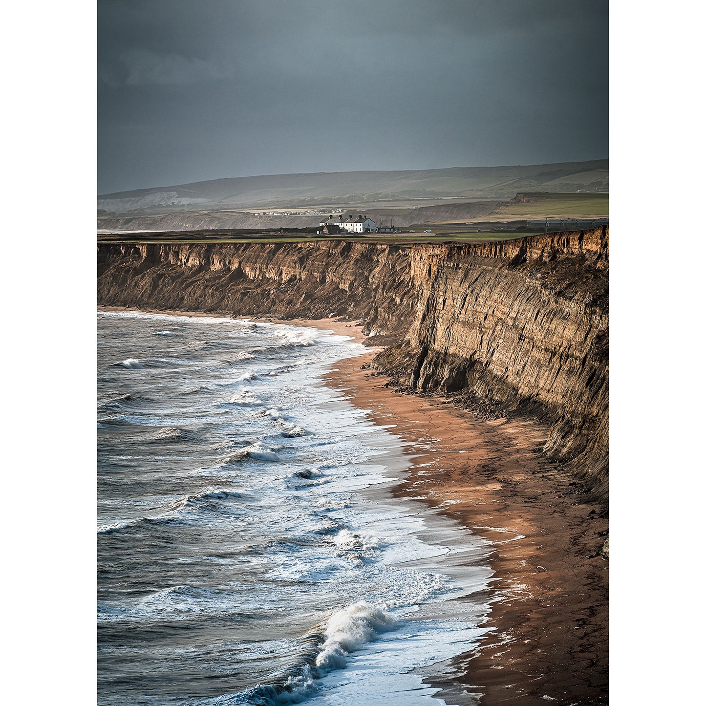 A train traveling along coastal cliffs under a Stormy seas at Chale sky with waves crashing onto the shore of Wight below, captured by Available Light Photography.