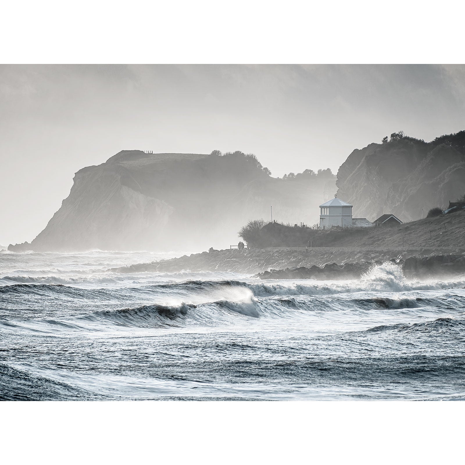 Coastal landscape with choppy waves and a white building against a backdrop of cliffs shrouded in mist on the Isle of Gascoigne featuring Woody Point from Ventnor by Available Light Photography.