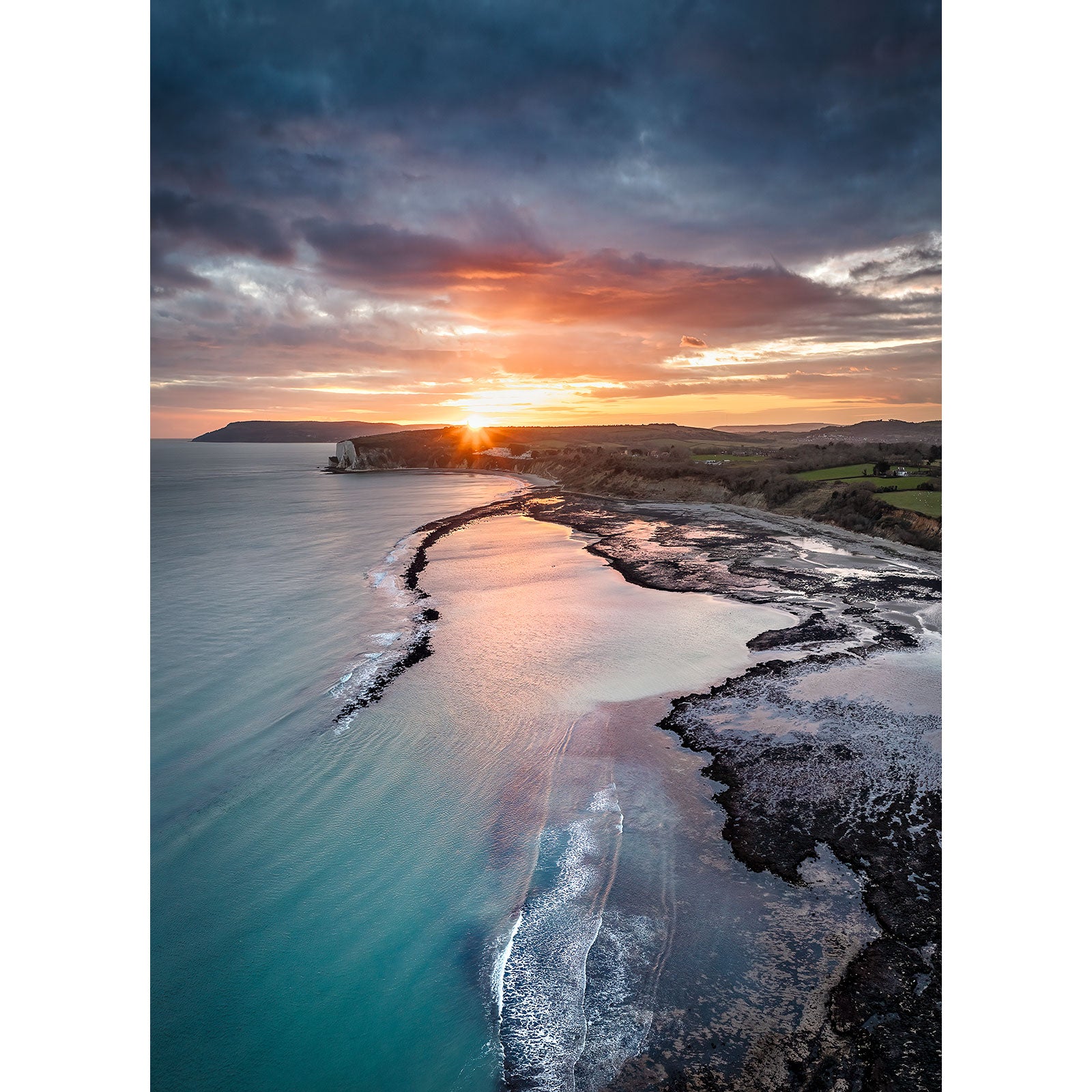 Sunset over a coastal landscape with a meandering river flowing into the sea near Whitecliff Bay by Available Light Photography.
