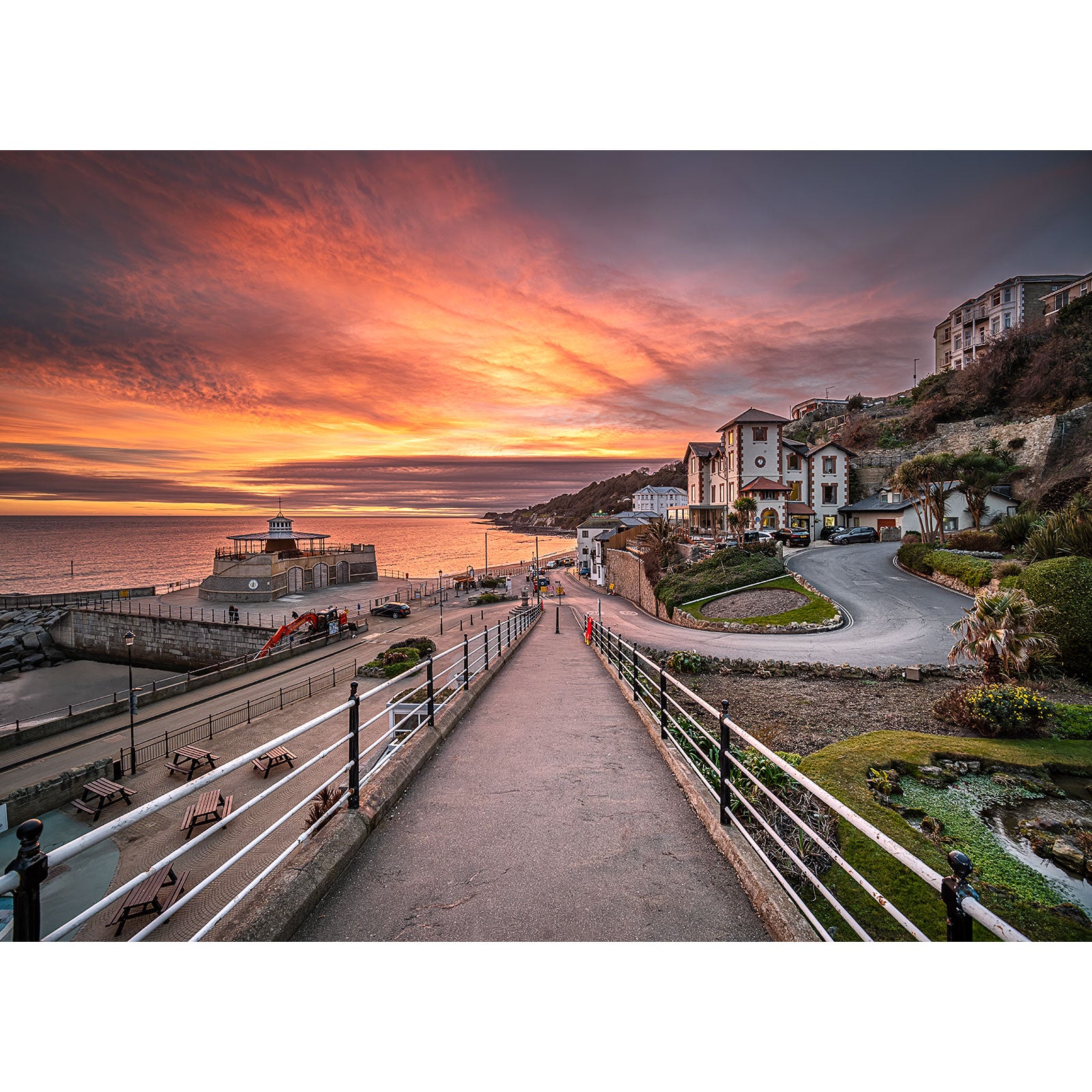 Sunset over a coastal promenade on the Isle of Wight with a dramatic sky, adjacent buildings, and a calm sea captured in Ventnor by Available Light Photography.